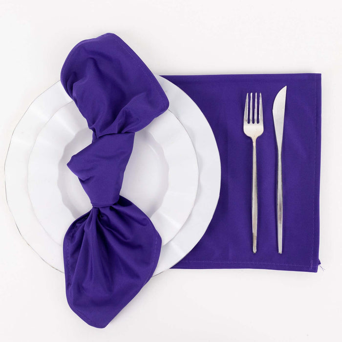 Purple napkin elegantly arranged on a white plate with silver cutlery.