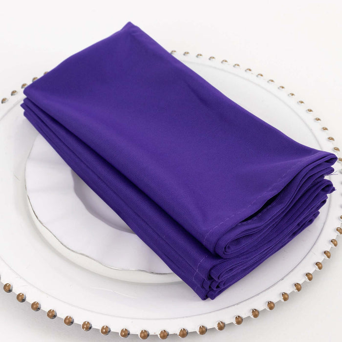 Purple fabric napkins neatly stacked on a plate.