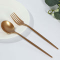 Gold cutlery set with spoon, fork, and chopsticks on white plate