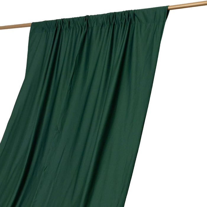 Green curtain draped on a wooden rod against a white background.