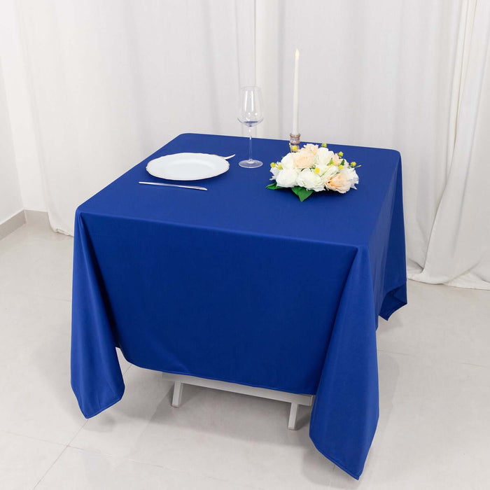 Elegant blue tablecloth set with white plate, wine glass, and floral centerpiece.