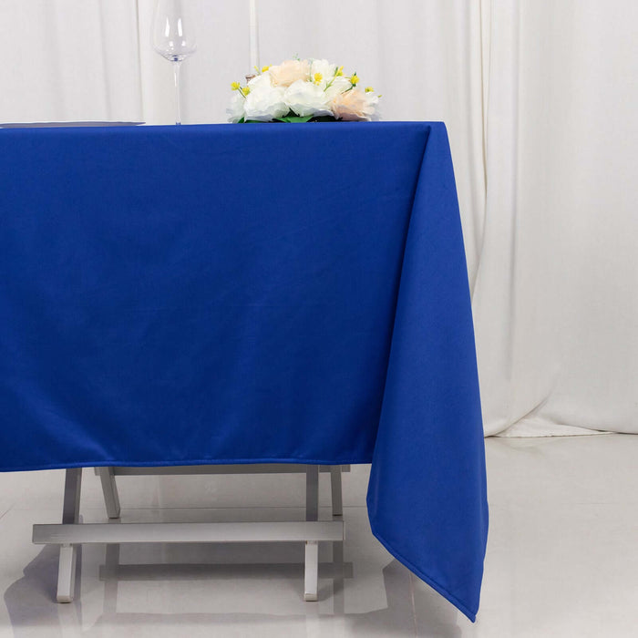 Blue tablecloth draping over a table with a glass and bouquet on top.