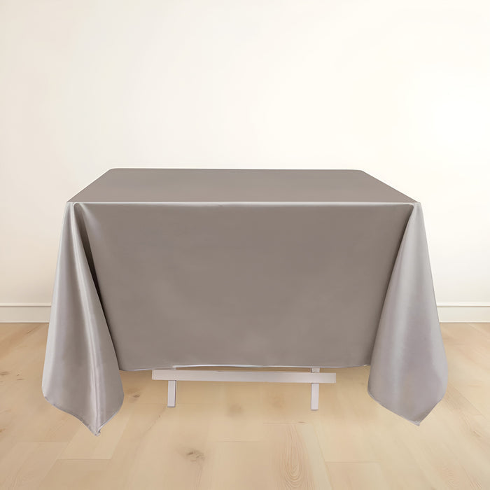 Gray tablecloth draped over a table on a plain backdrop.